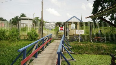 A lone police rank manning the Sophia entrance of the University of Guyana yesterday morning.