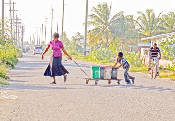 Benneta Kissoon and one of her boys fetching water from a kind-hearted neighbour to her home across the road along the Railway Embankment at Non Pareil, East Coast Demerara. (Photo by Arian Browne)