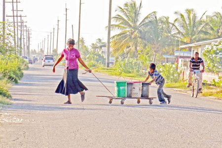 Benneta Kissoon and one of her boys fetching water from a kind-hearted neighbour to her home across the road along the Railway Embankment at Non Pareil, East Coast Demerara. (Photo by Arian Browne)