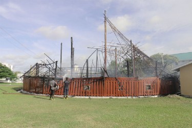 Fire fighters spraying water on the burnt building on September 9. (Stabroek News file photo) 