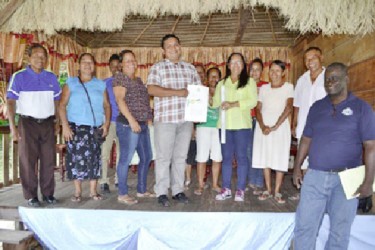 Minister of Amerindian Affairs, Pauline Sukhai (third from right on stage) handing over the land title document to Toshao of Batavia, Eon Boyal. (GINA photo) 