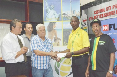 Wesley Tucker, Senior Marketing Officer of Fly Jamaica (right), hands over the two airline tickets to Michael Fung of the GBBC. 