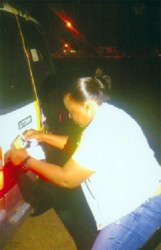 GWMO President Simona Broomes puts an anti-human trafficking sticker on a minibus at Mahdia. 