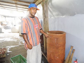 Anand Ramjass pointing to the new colour of his water barrel compliments of the water  supplied by GWI