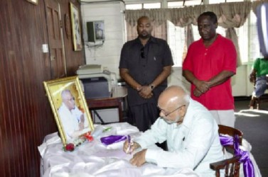 President Donald Ramotar signing the Book of Condolence for Leslie Melville at the Guyana Public Service Union, Shiv Chanderpaul Drive.  Standing at right is GPSU President Patrick Yarde. (GINA photo)