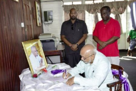 President Donald Ramotar signing the Book of Condolence for Leslie Melville at the Guyana Public Service Union, Shiv Chanderpaul Drive.  Standing at right is GPSU President Patrick Yarde. (GINA photo)