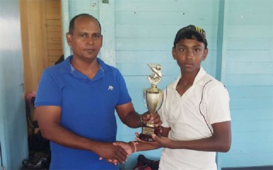 Kelvin Omroa receives his MVP trophy from Nazimul Drepaul, GCB Junior National Selector. (Orlando Charles photo)