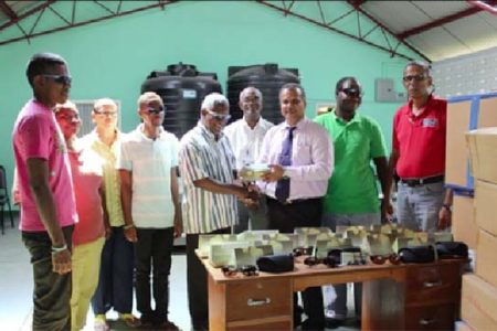 Food for the Poor Guyana Inc CEO Kent Vincent (at right) during the handing over of sunglasses to President of the Society for the Blind Cecil Morris.