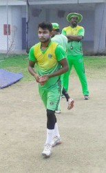 Davendra Bishoo goes through his motion yesterday during a training session at the Kensington Oval Ground, Barbados, as Head Coach Esaun Crandon looks on  