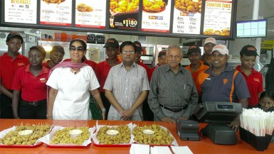 Finance Minister Ashni Singh (fourth from left) stands beside Chairman of Guyana Restaurant Incorporated, Raj L Singh (third from right) with staffs of the third Popeye’s restaurant. 