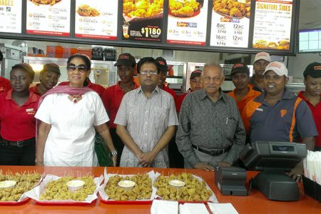 Finance Minister Ashni Singh (fourth from left) stands beside Chairman of Guyana Restaurant Incorporated, Raj L Singh (third from right) with staffs of the third Popeye’s restaurant. 