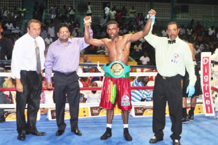 Minister of Finance, Ashni Singh and referee Eon Jardine raises the hand of the newly crowned WBC CABOFE light welterweight champion, Clive Atwell as president of the GBBC, Peter Abdool looks on. (Orlando Charles photo)

