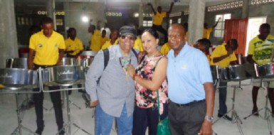 L Fitzroy ‘Rollo’ Younge (right) with Slingshot and his wife Ingrid when the couple visited Buxton on February 20. In the background are some members of the steel band.