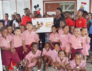 Elicia Chapman, Customer Service Officer of Massy Gas Products presents the television set to a teacher of Eccles Primary in the presence of pupils, teachers and parents. (Massy photo) 