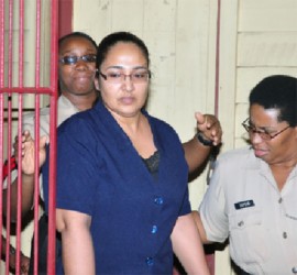 Bibi Sharima-Gopaul is escorted by police officers after exiting the courtroom following her sentencing yesterday for the murder of her daughter. She received 106 years in jail. (Orlando Charles photo)