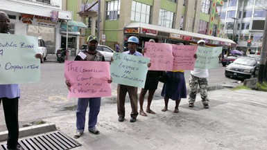 Former Precision Woodworking Limited employees yesterday protesting in front of Republic Bank on Camp Street demanding payments owed to them after the company was forced to shut down. 