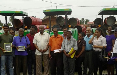 Minster Norman Whittaker stands with the overseers and chairpersons in front of the new tractors and trailers