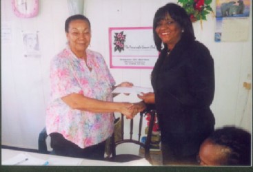 Director of the Periwinkle Club Luna Chung (left) receives the cheque for $1 million from Attorney Gem Sanford-Johnson (right). 