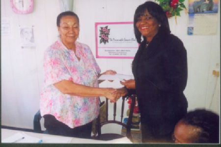 Director of the Periwinkle Club Luna Chung (left) receives the cheque for $1 million from Attorney Gem Sanford-Johnson (right).
