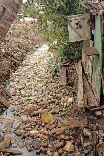 A young boy stares out of his backdoor which overlooks the rising garbage.