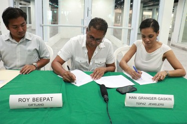 Giftland’s Roy Beepat (centre) and Topaz’s Han Granger-Gaskin signing contract. 