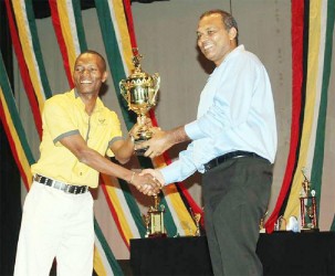 Roger ‘Young Bill Rogers’ Hinds (left) receives his winning trophy from Minister of Culture Frank Anthony.