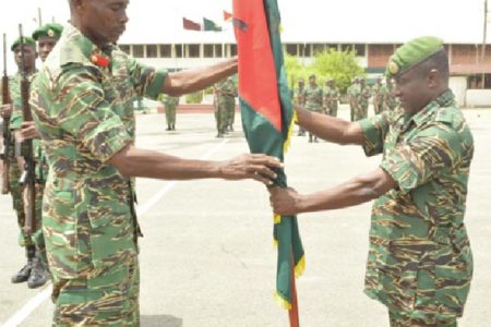 Col Wilbert Lee (left) officially hands over the Unit Colours to Lt Col Terry Benn on Thursday during his farewell parade at Hard Square, Camp Stephenson. (Guyana Defence Force photo)