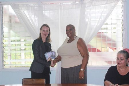 High Commissioner of Canada Dr Nicole Giles (left) hands over DVDs featuring discourses on sexual violence to Rainbow House representative Namela Henry
