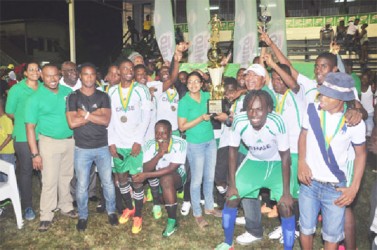 Owner and principal of Chase Academy Henry Chase (centre) receiving the championship trophy from Milo Brand Manager Renita Seethal while members of the newly crowned champs and the Petra Organization look on 