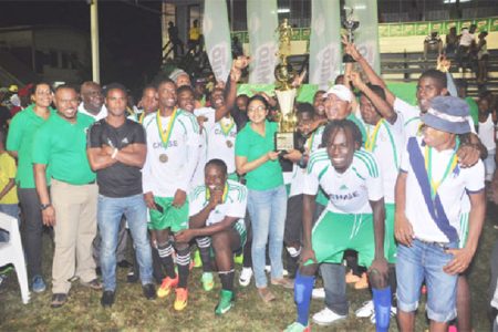 Owner and principal of Chase Academy Henry Chase (centre) receiving the championship trophy from Milo Brand Manager Renita Seethal while members of the newly crowned champs and the Petra Organization look on
