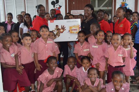 Elicia Chapman, Customer Service Officer of Massy Gas Products presents the television set to a teacher of Eccles Primary in the presence of pupils, teachers and parents. (Massy photo)