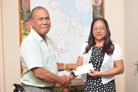 Minister of Amerindian Affairs Pauline Sukhai  handing over a cheque to Manoel “King Perai” Ferreira at the Ministry of Amerindian Affairs, Thomas and  Quamina Streets (GINA photo)