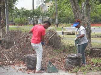 Two members of the Guyana Shines project cleaning up Waterloo Street last Sunday. (Rae Wiltshire photo)