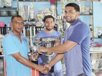 In picture Managing director of Trophy stall Ramesh Sunich presents one of the trophies to be competed for at the Guyana Cup Fever horse race meet to organiser Nazrudeen ‘Jumbo Jet’ Mohammed Jr., while overseas-based Guyanese Ricky Azrula holds one of the trophy at centre.  The Trophy Stall apart from providing all the trophies for the Guyana Cup Fever horse race meet will also be providing the trophies for the top jockey, runner up, stable and trainer.   