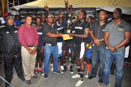 Beterverwagting A’s captain Delroy Deen collects the championship trophy from Banks DIH Limited East Coast Area Manager Clive Pellew while members of the winning team, Banks DIH and Petra Organisation officials look on. (Orlando Charles photo)
