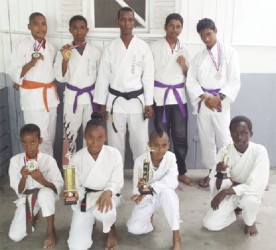 Members of the successful Black Cobra Karate Club of Parfaite Harmonie alongside sensei Lloyd Ramnarine (centre) displaying their respective medals and trophies earned during the Guyana Classic of Classic Martial Arts Tourney