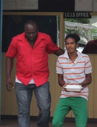 Imran Ramsaywack (right) being escorted out of the Cove and John Police Station yesterday. 