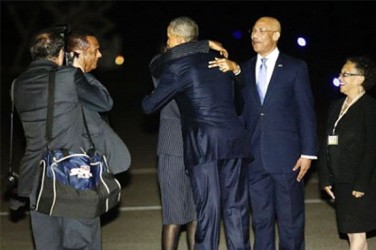 U.S. President Barack Obama (C, back to camera) gets a hug from Jamaica's Prime Minister Portia Simpson Miller as he arrives aboard Air Force One at Norman Manley International Airport in Kingston, Jamaica April 8, 2015.  Reuters/Jonathan Ernst