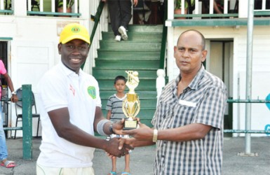 Essequibo MVP Keanu Harry receives his trophy from GCB Chairman of Junior Selectors Nazimul Drepaul.