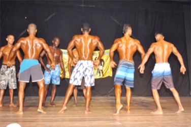 The top Men’s Physique competitors displaying a back pose. From left is Yannick Grimes (3rd place), Emmerson Campbell (first), Caerus Cipriani (2nd place) and Chetram Nagesar (fourth place).