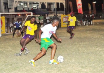 Eon Alleyne (white) of Festival City on the attack against Kitty Weavers during their group stage match in the Busta Football Championships 