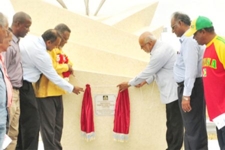 President Donald Ramotar (right) and Prime Minister Samuel Hinds ceremoniously unveiling the plaque at the gateway of the National Track and Field Centre and Football Facility at Leonora yesterday. (Orlando Charles photo)
