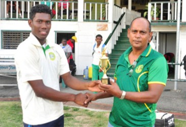 Kemo Paul receives his trophy from GCB Chairman of Junior National Selectors Nazimul Drepaul. (Orlando Charles photo) 