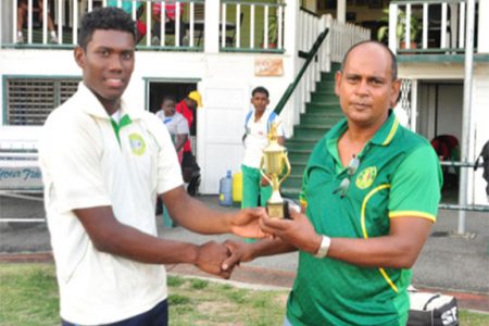 Kemo Paul receives his trophy from GCB Chairman of Junior National Selectors Nazimul Drepaul. (Orlando Charles photo)
