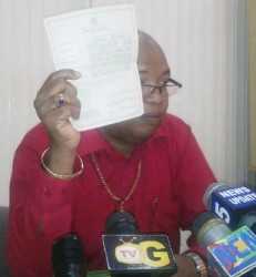 Minister Juan Edghill holds a copy of his birth certificate which he says is proof that he has never changed his name. 