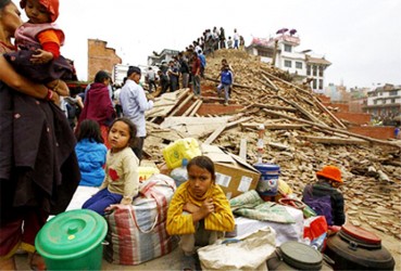 People sit with their belongings outside a damaged temple in Bashantapur Durbar Square, April 25, 2015. REUTERS/Navesh Chitrakar
