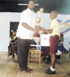 President of the Linden Fund USA Keith Semple presents the winning trophy for the Linden Inter-primary schools Spelling Bee competition to the overall winner Denzil Yaw of the Amelia’s Ward Primary School. 