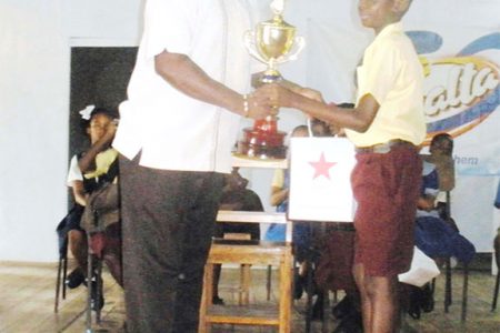 President of the Linden Fund USA Keith Semple presents the winning trophy for the Linden Inter-primary schools Spelling Bee competition to the overall winner Denzil Yaw of the Amelia’s Ward Primary School.
