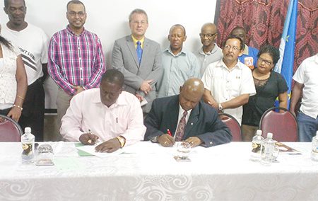 FAO Representative Reuben Robertson (right) signing the agreement for the pilot timber project with Manager of the Forestry Training Centre Inc Quancy Bremmer. Also in photo are: Natural Resources and Environment Minister Robert Persaud (third, left); Head of the European Delegation in Guyana, Ambassador Robert Kopecky (fourth, left) and some of the recipients of the project.
