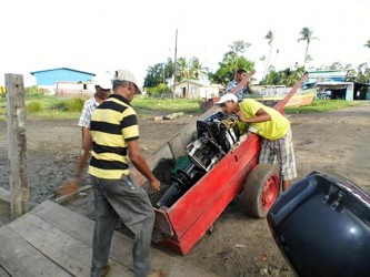 Many hands make light work: Transporting the engine from wharf to boat. (Photo by Jannelle Williams)